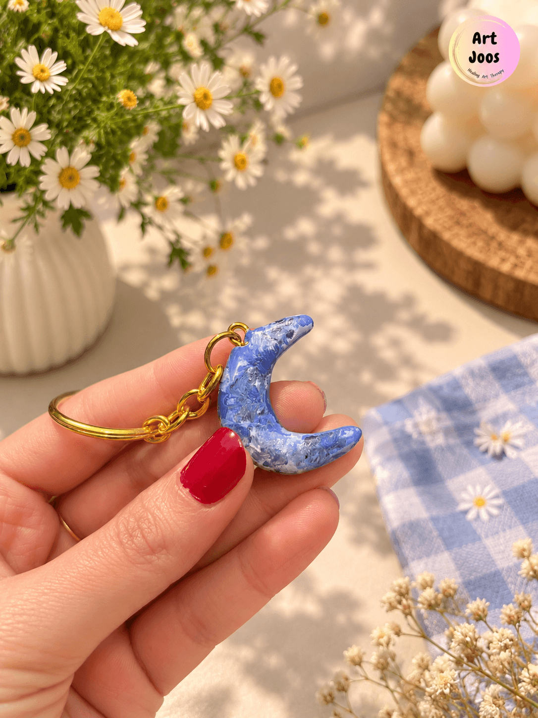 Handmade crescent moon clay keychain in marbled blue, white, and grey, attached to a gold-tone metal chain and circular keyring.